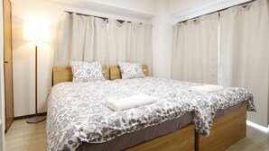 Una camera da letto con un letto in legno, un comodino, una lampada e una finestra con tende.