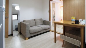 Un ambiente compatto con un divano, un tavolo in legno e uno specchio.