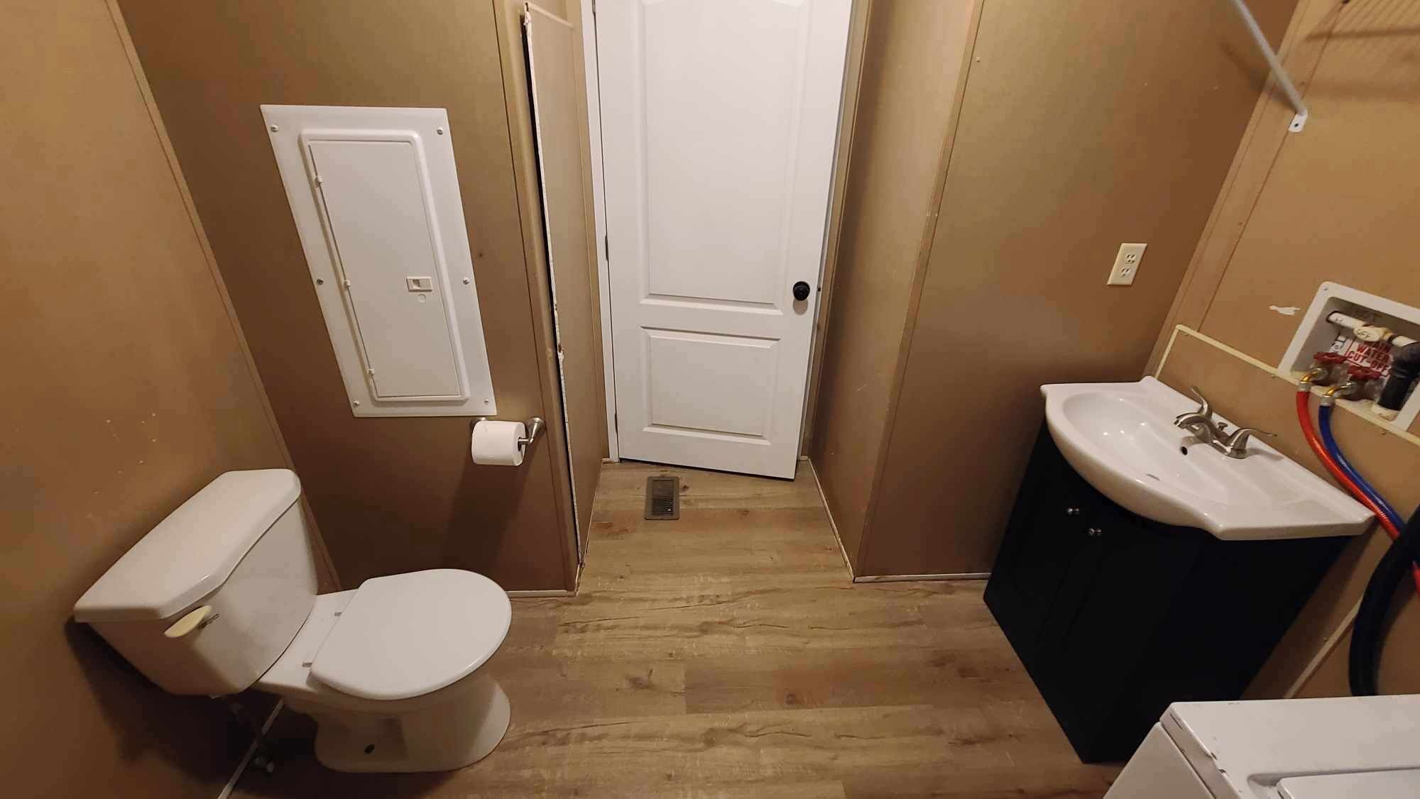 A small bathroom with a toilet, sink, and door.