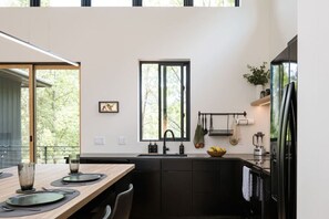 A modern kitchen with a large window, black cabinets, and a dining area with a table set for two.