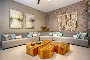 A modern living room with a sectional sofa, a wooden coffee table, and abstract paintings on the wall. - 1BR w/ Rooftop Pool, Bar + City Views | Old Town (Puerto Vallarta)
