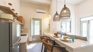 Une cuisine moderne dotée d’un réfrigérateur en acier inoxydable, d’une étagère en bois avec des bocaux, d’un climatiseur intégré et d’un bar pour le petit-déjeuner avec des sièges.