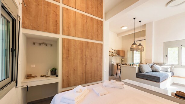 Une chambre moderne dotée d’un grand lit, d’une armoire intégrée, d’un petit coin cuisine et d’un espace détente avec un canapé et une table à manger.