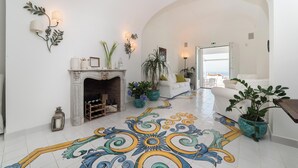 Eine großzügige Lobby mit Kamin, dekorativen Wandleuchten, Topfpflanzen und einem gefliesten Boden mit Blumenmuster.