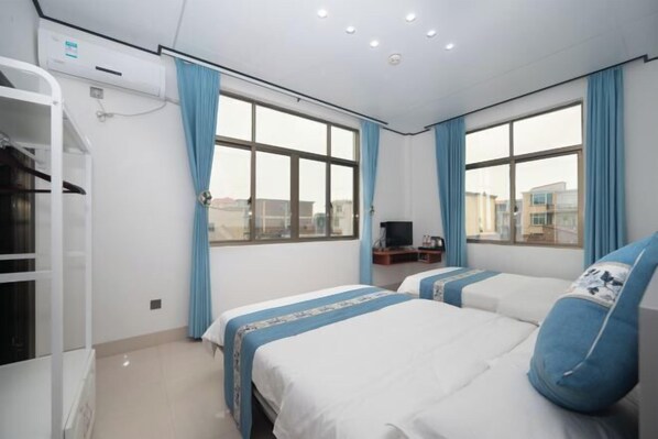 A hotel room with two beds, a TV, and a window with curtains. - Meizhou Island Beach House Resort Hotel (Putian)