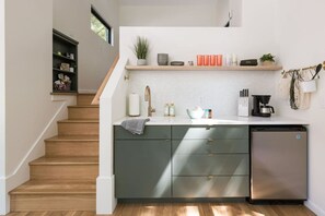 Una cucina moderna con lavastoviglie integrata, una scala in legno e un piccolo ripiano con utensili da cucina.