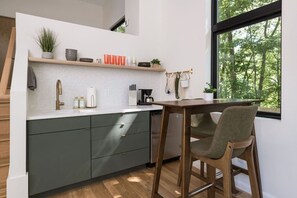 Una cucina moderna con lavastoviglie integrata, un tavolo da pranzo in legno e vista sull'esterno attraverso un'ampia finestra.
