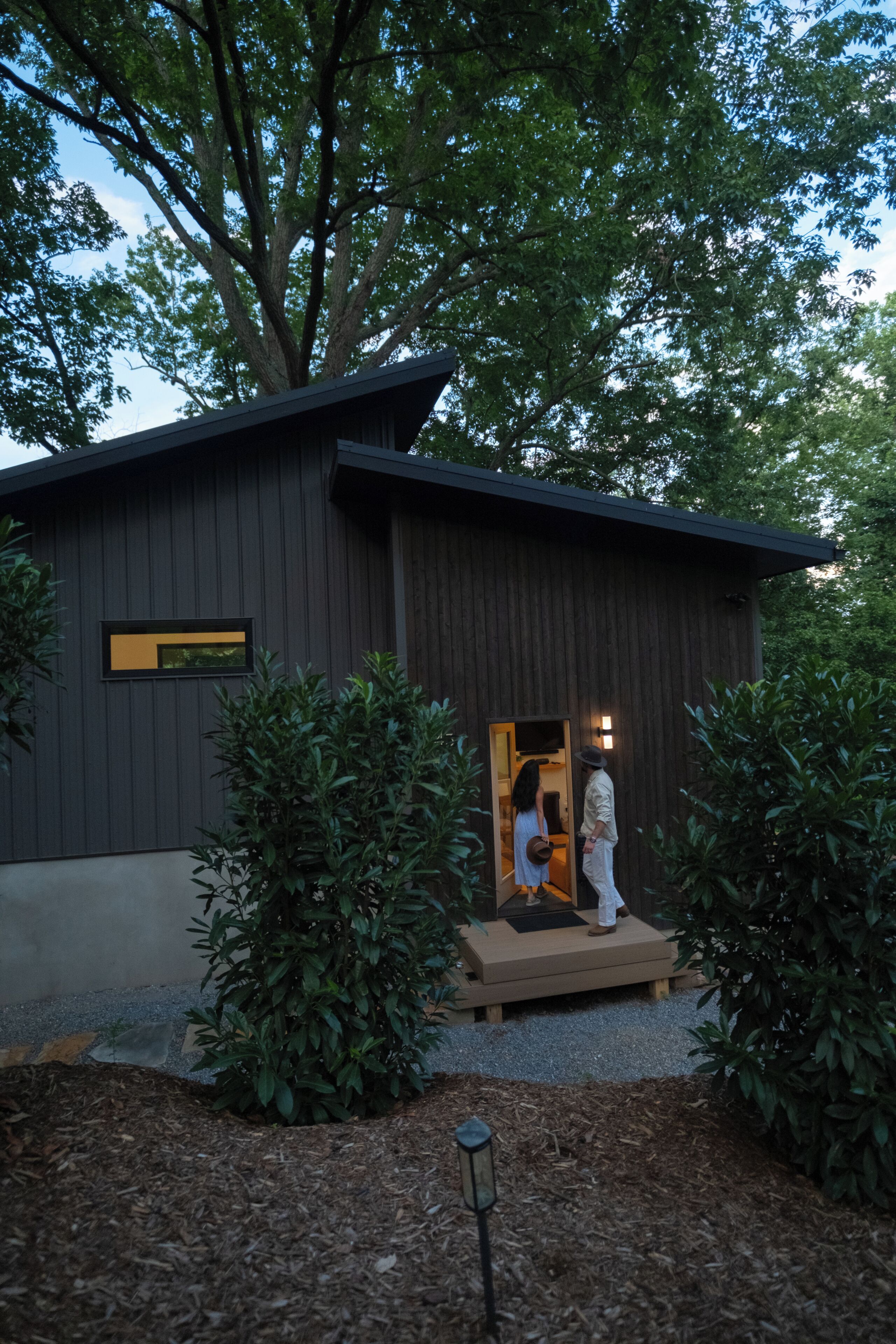 A modern building with a dark facade, a visible entrance, and a small porch area.