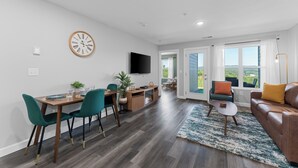 A modern living room with a fireplace, a dining area with teal chairs, and a large window offering a view. - Summer Specials! #1 Location, Arcade, Near SDC, Modern, Panoramic Views, Pools (Branson)