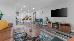 A modern living room with a flat-screen TV, a fireplace, and a dining area with chairs and a table. - Summer Specials! #1 Location, Arcade, Near SDC, Modern, Panoramic Views, Pools (Branson)