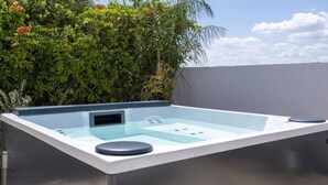 Un espace spa moderne doté d’une paroi en verre, d’un panneau de commande et d’un coin salon.