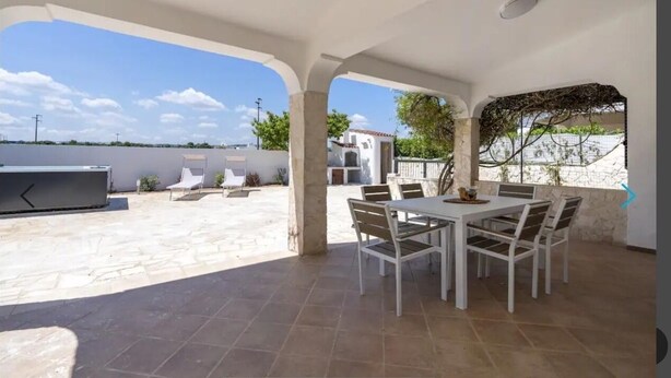Une terrasse extérieure avec une table et des chaises pour les repas, un barbecue et une vue sur la mer.
