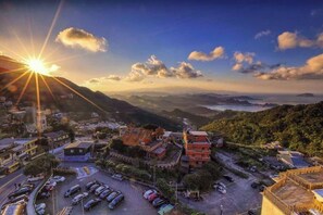 An aerial view of a town with buildings, a parking lot, and a mountainous landscape. - Jiufen Sunshine (New Taipei City)