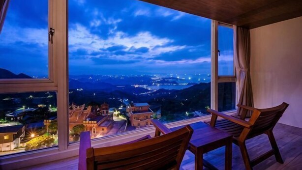 A room with a large window, a wooden table, and two chairs. - Jiufen Sunshine (New Taipei City)