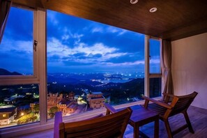A room with a large window, a wooden table, and two chairs. - Jiufen Sunshine (New Taipei City)