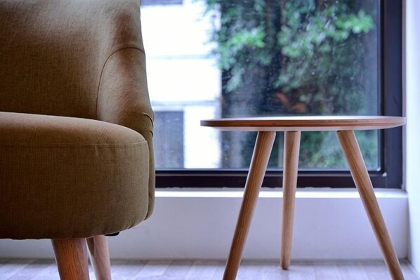 A room with a window, a chair, and a small wooden table.