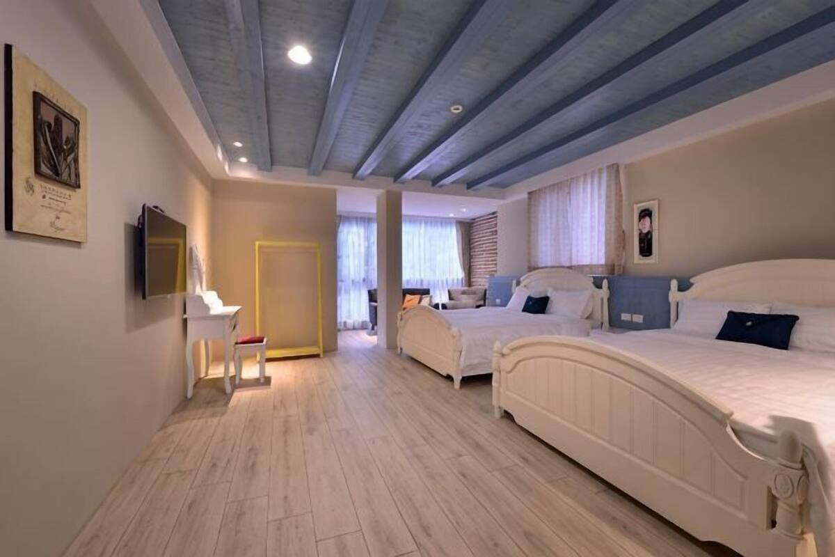 A bedroom with two beds, a desk, and a TV.