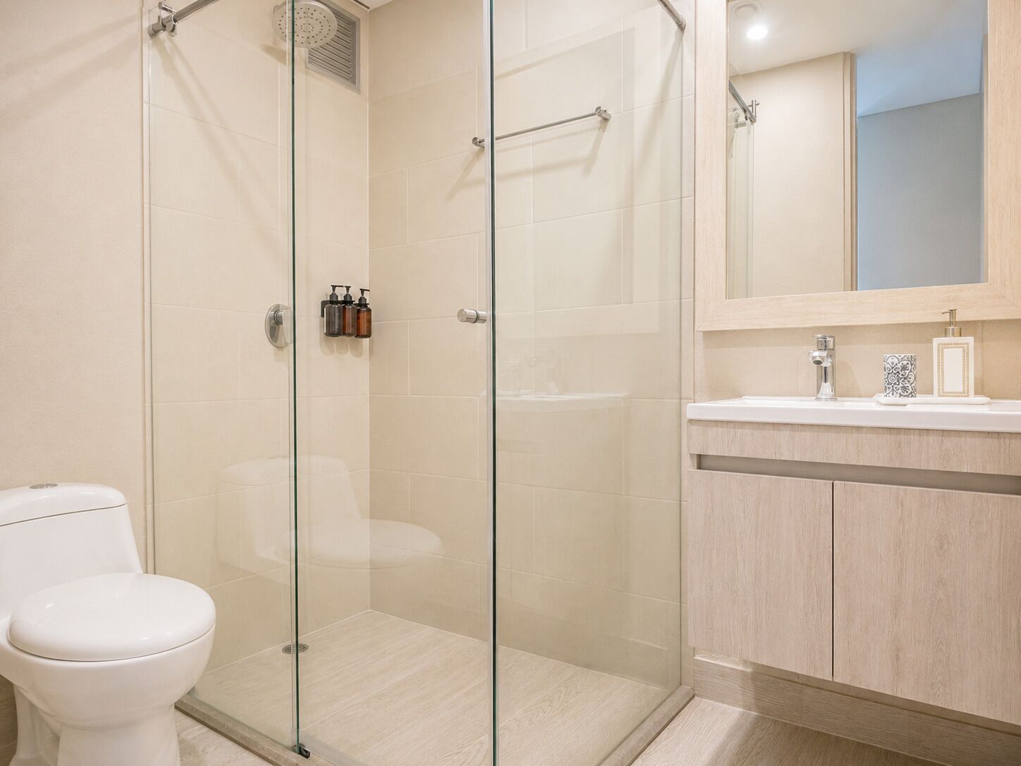 Une salle de bain avec une douche à parois de verre, des toilettes et un meuble-lavabo avec un miroir et des articles de toilette.