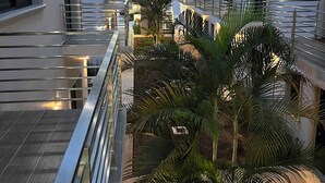 Un edificio residencial de varios niveles con balcones, escaleras y un patio central con palmeras.