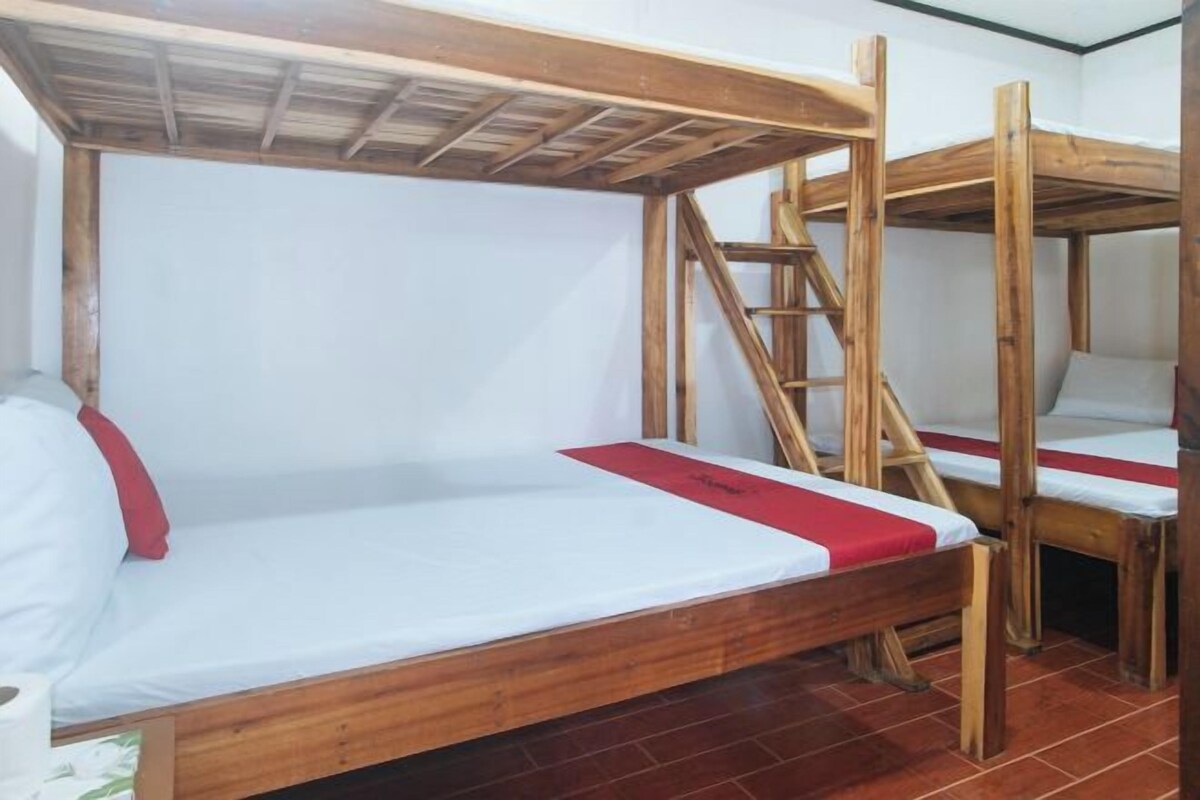 Una habitación con literas, vigas de madera y suelo de baldosas.