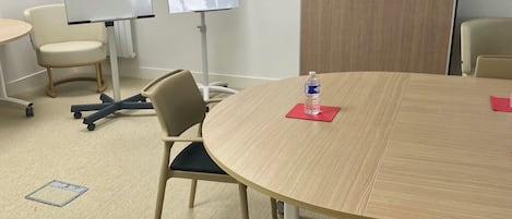 Et mødelokale med et rundt bord, stole, en hvidtavle og en flipoverstander.
