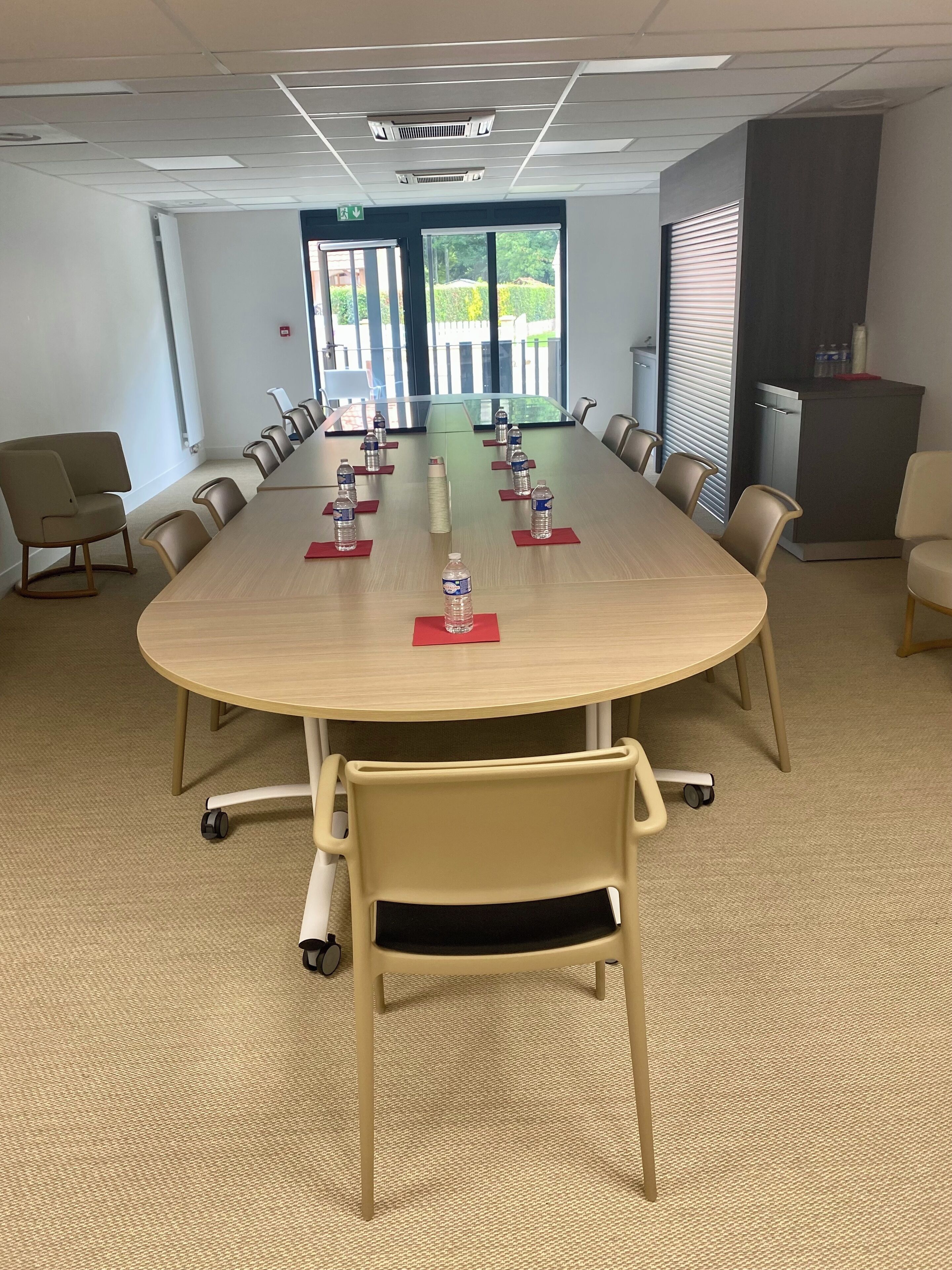 A conference room with a long table, chairs, and water bottles on placemats.