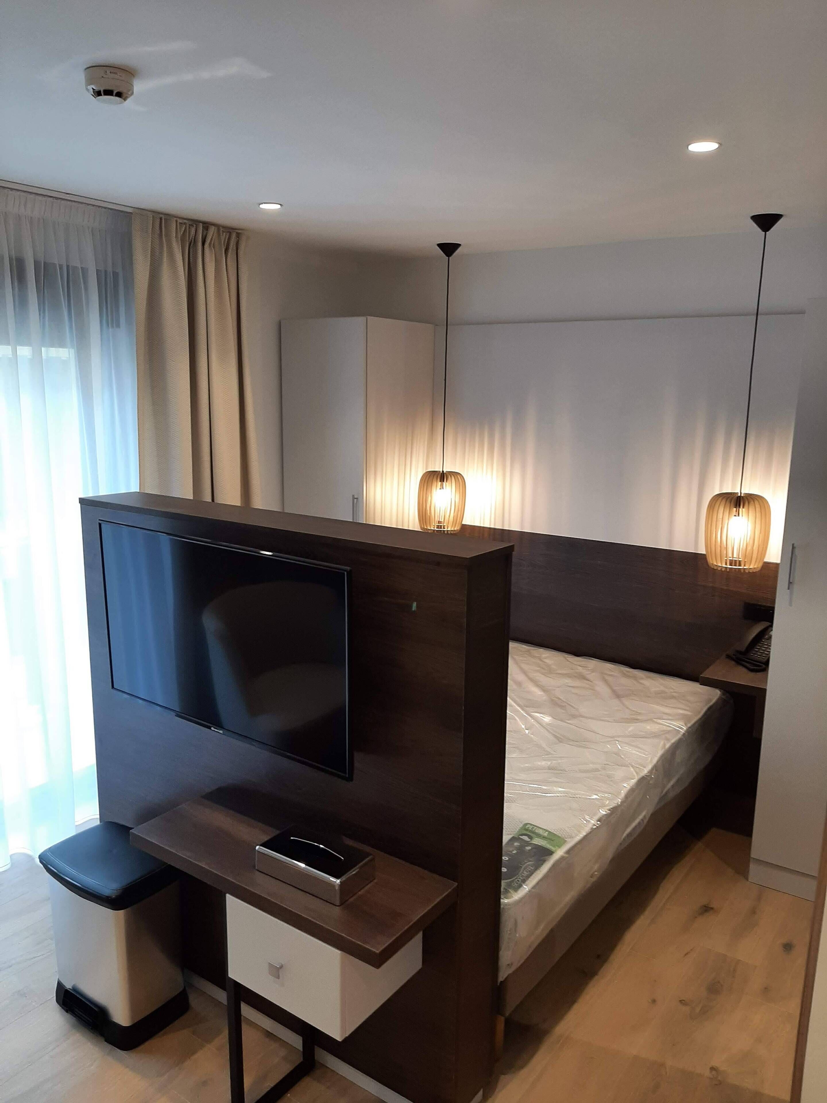 A modern bedroom with a TV, bedside table, and a bed.