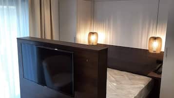 A modern bedroom with a TV, bedside table, and a bed.
