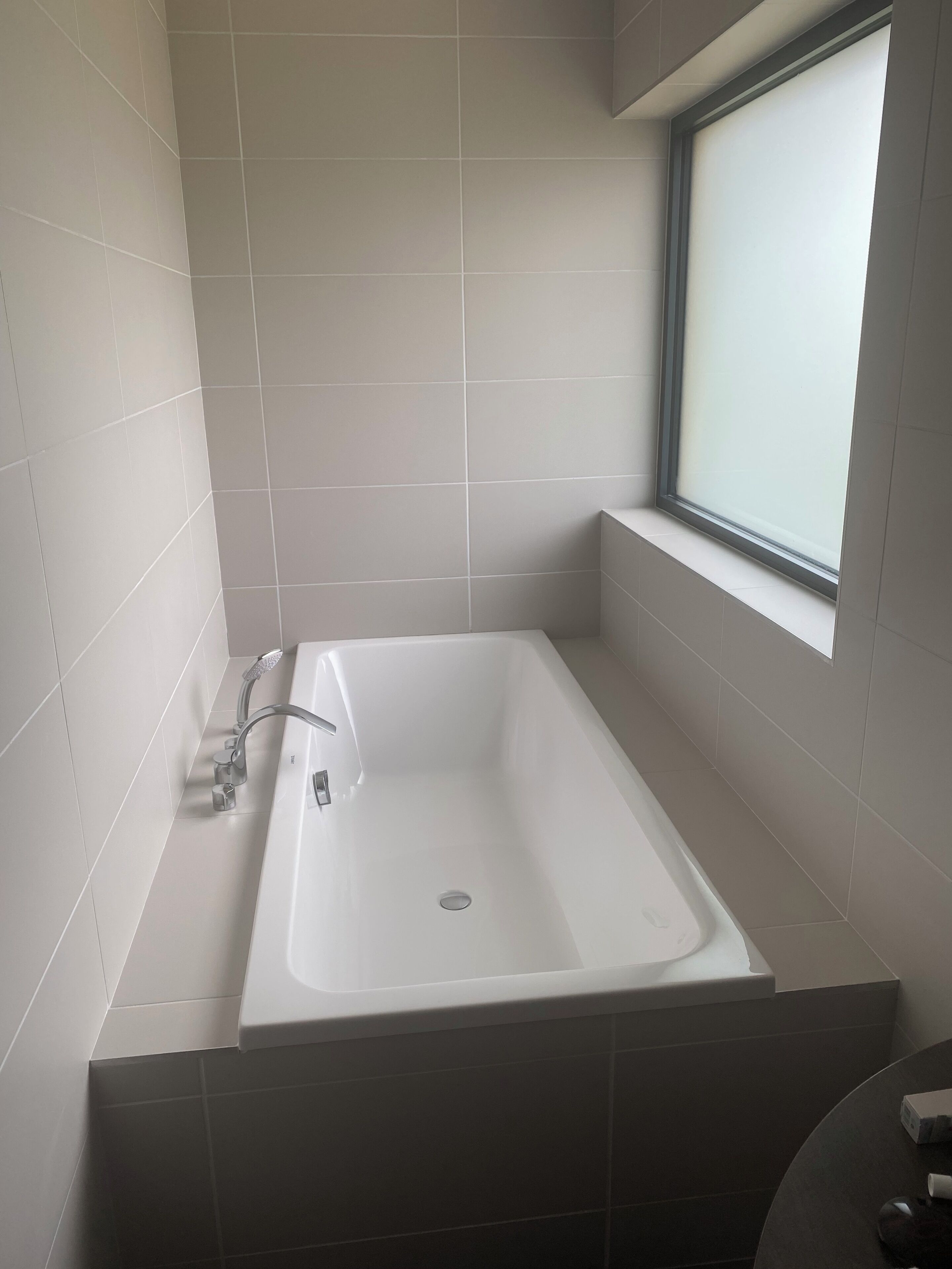 Une salle de bain moderne avec une baignoire rectangulaire, une fenêtre et un espace douche.