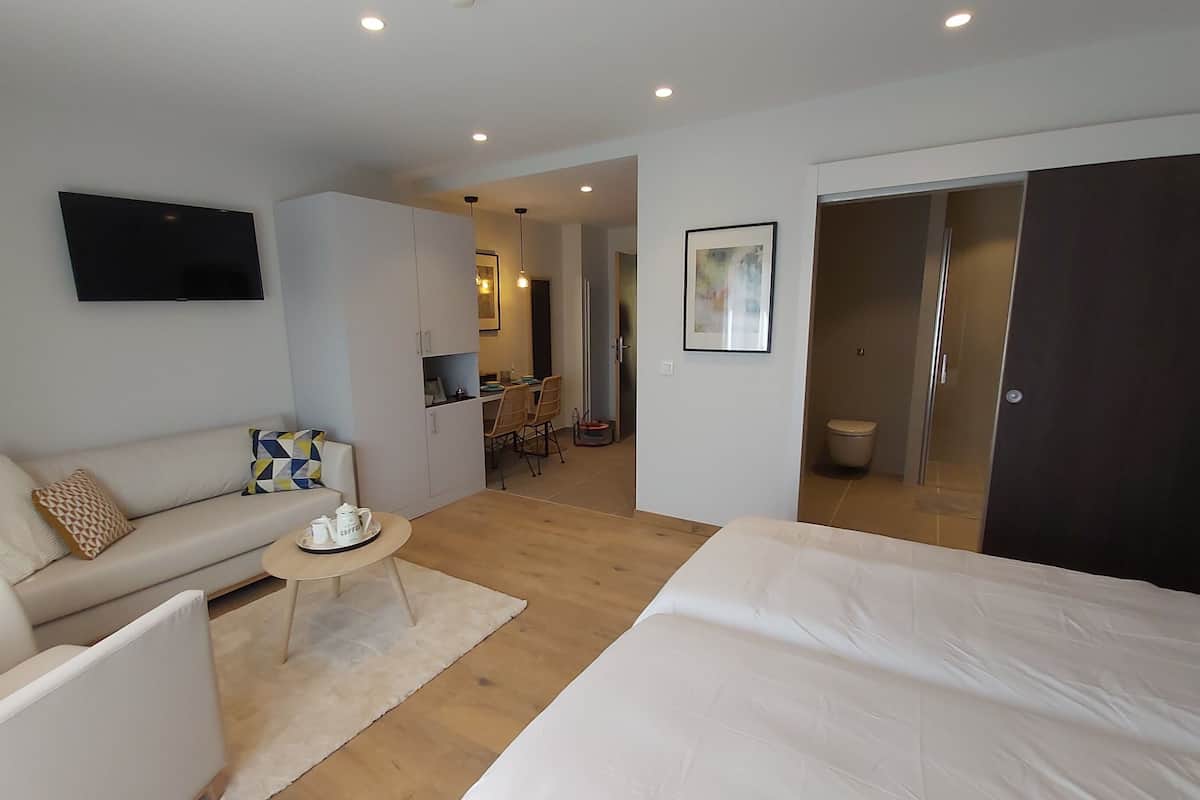Een moderne hotelkamer met een groot bed, een bank, een salontafel en een aan de muur bevestigde televisie.