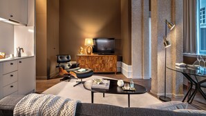 Een moderne woonkamer met een flatscreen televisie, leren bank en een eethoek met een glazen tafel en stoelen.