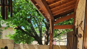 Un espace extérieur abrité, doté d’un banc et d’une table, d’un sol en béton et d’une structure en bois formant une pergola.