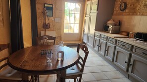 A kitchen with a wooden table, chairs, cabinets, a microwave, and a window with a view.