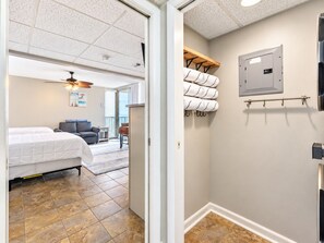 Habitación de hotel con cama, ventilador de techo, baño con toallas y vistas al exterior.