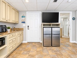 Una cocina con un refrigerador de doble puerta, un microondas y un televisor de pantalla plana.