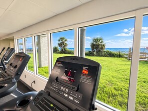 A gym with treadmills and a view of the ocean through large windows. - Beachfront Studio | Gulf Views, Balcony + Pools (Panama City Beach)
