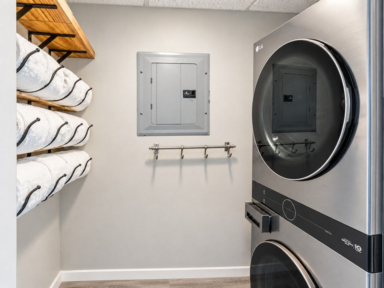 A laundry room with a washing machine, dryer, and a towel rack with towels.