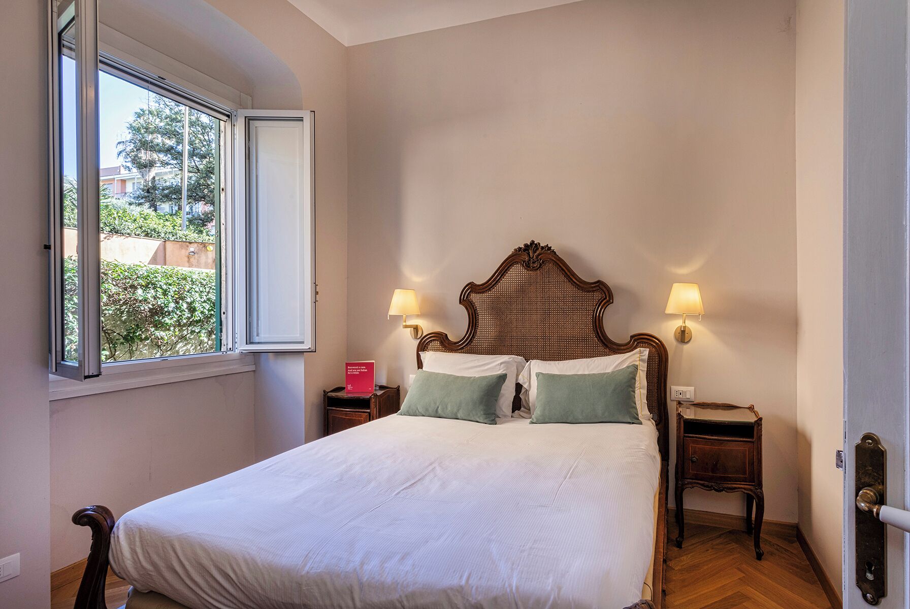 A bedroom with a large bed, two bedside tables, a window, and a door.