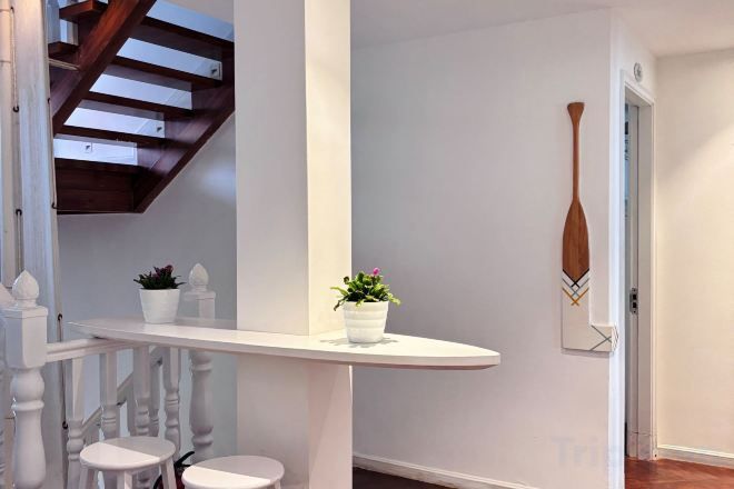 Un pasillo con barandilla blanca, una planta en maceta y una puerta.