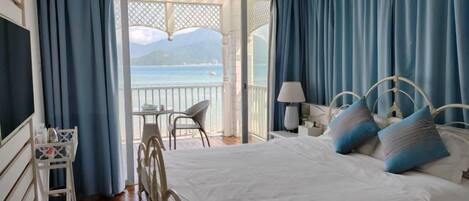 Une chambre avec un lit, une chaise, une table et une vue sur la mer.