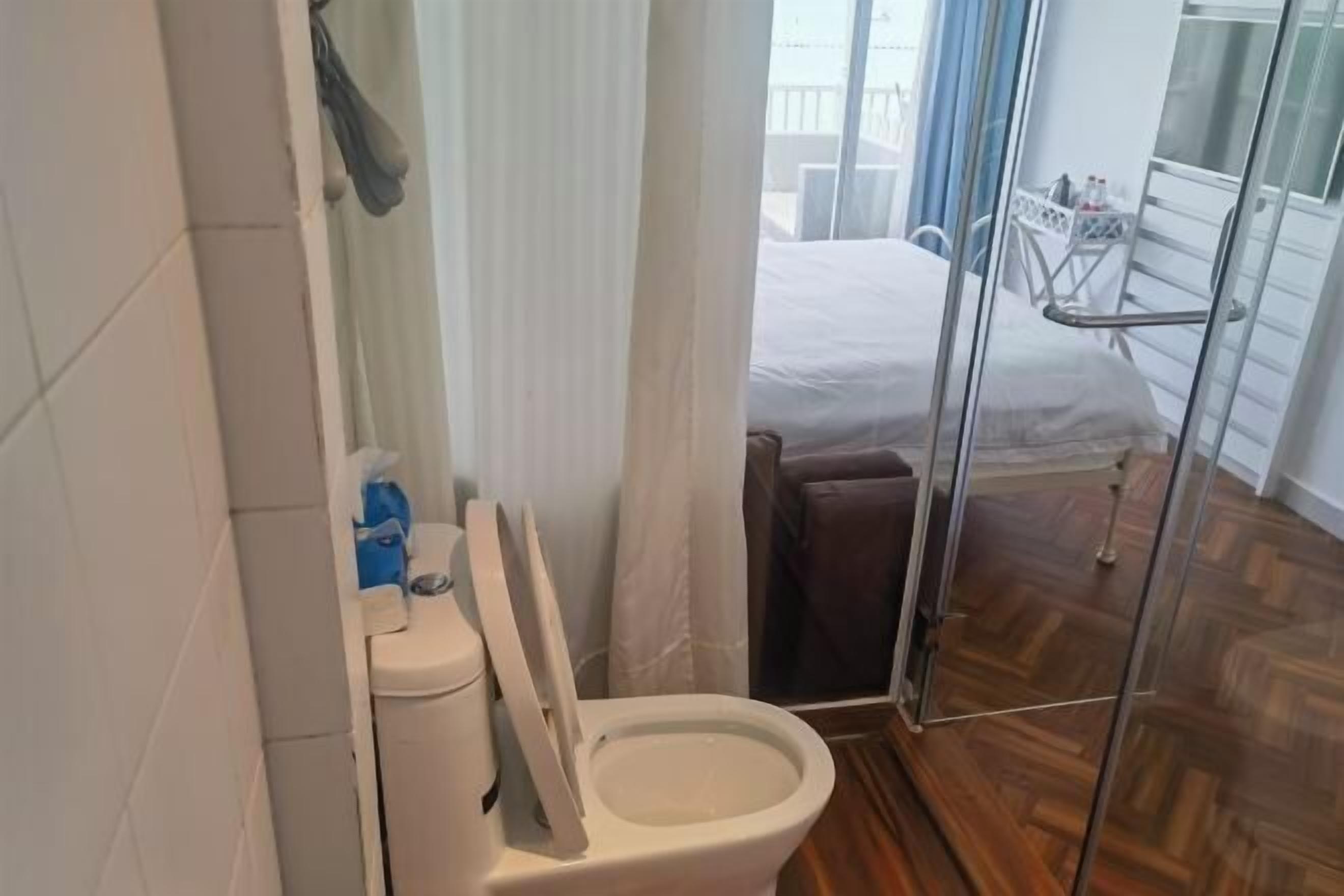 Une salle de bain équipée de toilettes, d’une douche et d’une porte vitrée donnant sur un balcon.