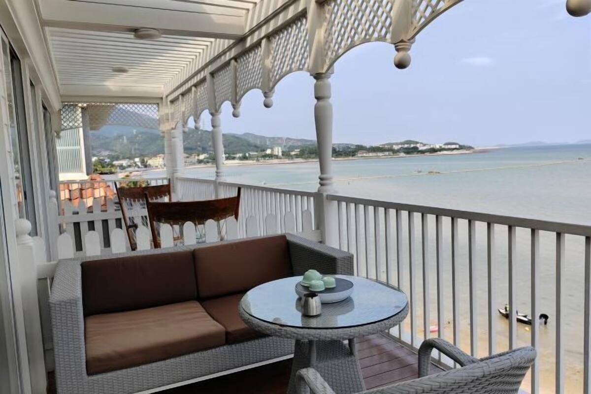 A balcony with a sofa, a round table, and wicker chairs.