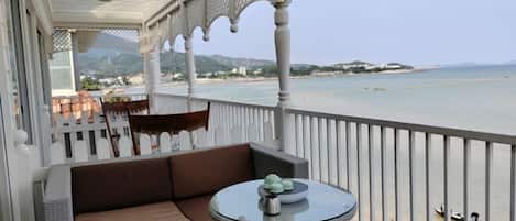 A balcony with a sofa, a round table, and wicker chairs.