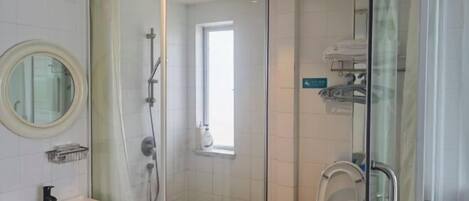 A modern bathroom with a glass-enclosed shower, a toilet, and a sink with a mirror.