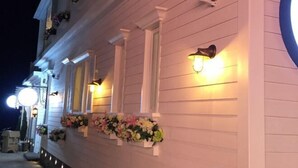 A white building with multiple windows, some with shutters, and exterior wall-mounted lights. - Kela Coast Seaside Inn (Shenzhen)