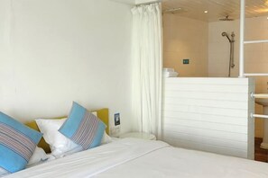 A hotel room with a bed, pillows, a shower area, and a sink. - Kela Coast Seaside Inn (Shenzhen)
