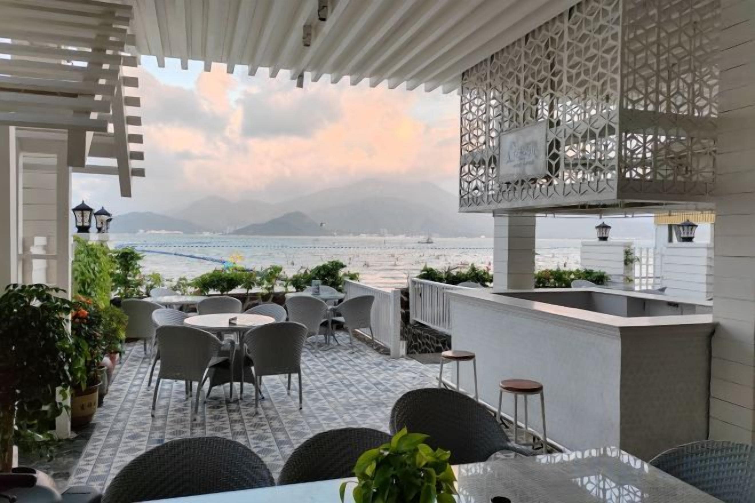 Una terraza con asientos al aire libre, vista al mar y una estructura blanca decorativa.