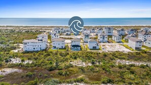 Une zone résidentielle côtière avec de nombreuses maisons blanches, dont certaines sont dotées de balcons, et une plage en arrière-plan.