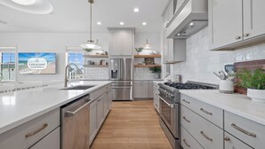 Une cuisine moderne avec des meubles blancs, des appareils en acier inoxydable et un plancher en bois.