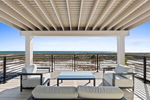 Un espacio de estar al aire libre cubierto con vista a la playa y al océano.